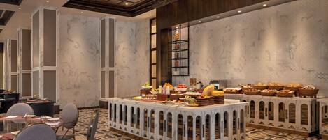 A hotel dining area with a buffet setup, including a variety of food items and a decorative shelf.