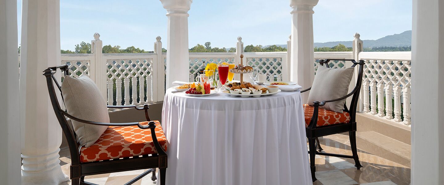 A balcony with a table set for breakfast, featuring a variety of food and drinks.