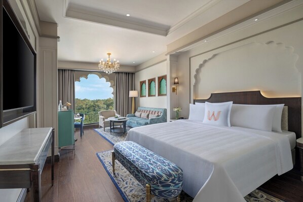 A hotel room with a large bed, a TV, a desk, a sofa, and a view of the outdoors. - Welcomhotel By ITC Hotels Jabalpur (Jabalpur)