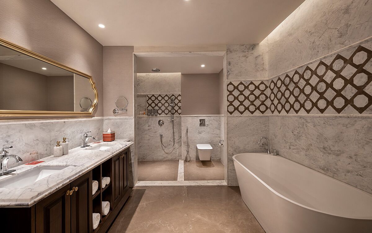 Ein modernes Badezimmer mit einer freistehenden Badewanne, einem Doppelwaschtisch mit großem Spiegel und einem Duschbereich mit Musterwand.