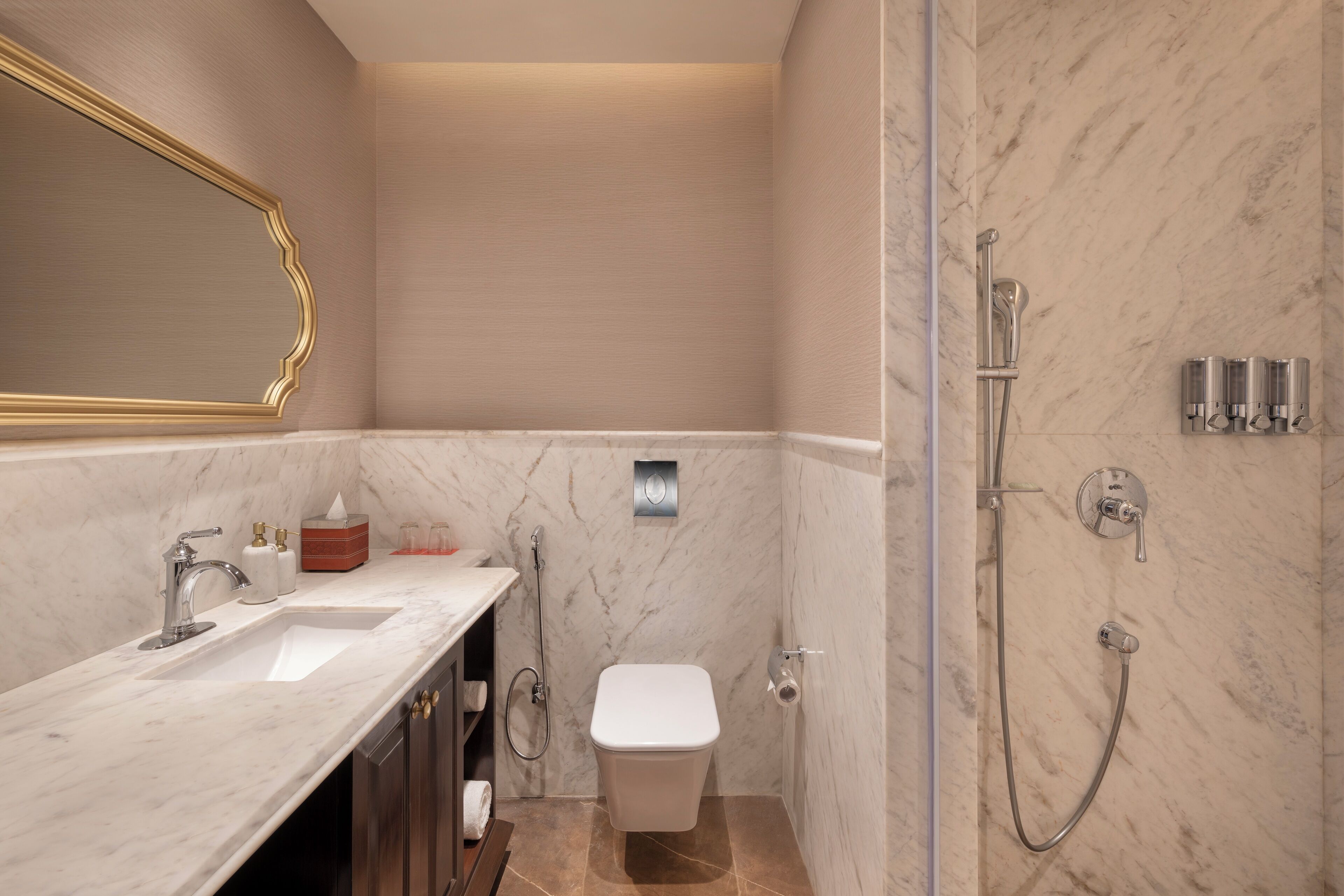 A modern bathroom with a marble sink, a toilet, and a shower area.