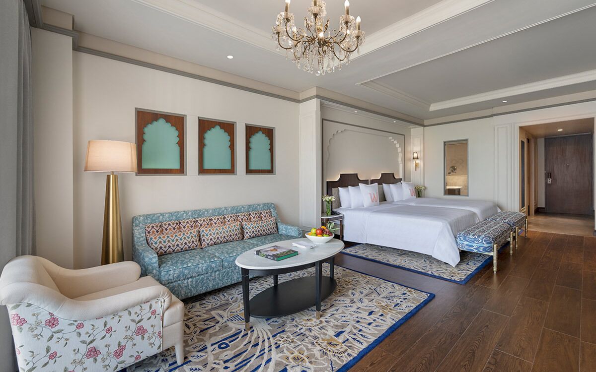 Een hotelkamer met een bank, fauteuil, bed en een ronde salontafel.