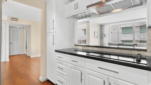 A modern kitchen with white cabinetry, black countertops, and stainless steel appliances. - Bay Harbor Sunset Two Bedroom (Bay Harbor Islands)