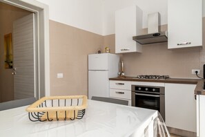A modern kitchen with white cabinets, a built-in oven, a gas stove, and a refrigerator. - Villino Lella | holiday house in Torre Lapillo (Porto Cesareo)