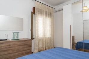 Ein Schlafzimmer mit einem Bett, einem Schminktisch, einem Spiegel und einem Fenster mit Vorhängen.