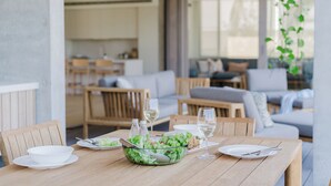 Una mesa de comedor con platos, tazones y vasos, rodeada de sillas de madera.