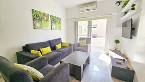 A modern living room with a grey sofa, yellow cushions, a coffee table, and a TV on the wall. - Blue Sky Ocean Retreat (Larnaca)
