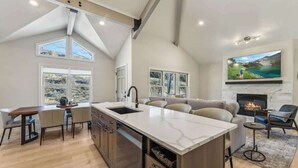 A modern kitchen with a central island, dining area, and a fireplace.