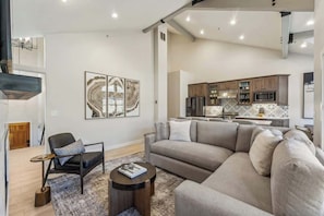 Un salon moderne avec un canapé d’angle, une petite table basse ronde et un fauteuil.