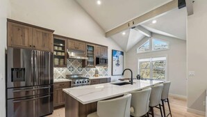 A modern kitchen with a central island, stainless steel appliances, and a large window providing natural light.