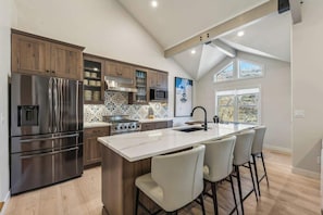 Una cocina moderna con una isla central, electrodomésticos de acero inoxidable y un ventanal que proporciona luz natural.