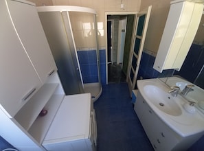 Ein Badezimmer mit weißem Waschbecken, einem Spiegel und einer Dusche.