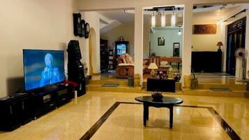 A spacious living room with a television, a piano, and a coffee table.