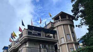 A traditional hotel with multiple flags, a balcony, and a sign indicating it is a traditional hotel. - TRADITIONAL HOTEL AND RESTAURANT (Kurseong)