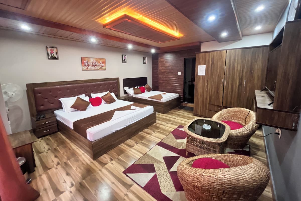 A hotel room with two beds, a TV, a wardrobe, and wicker chairs.