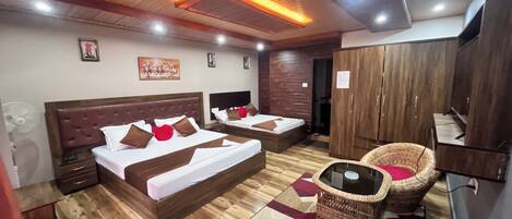 Habitación de hotel con dos camas, televisión, armario y sillas de mimbre.