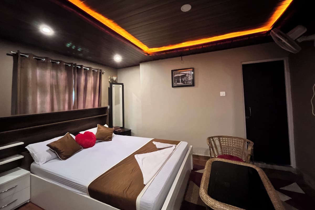 A hotel room with a bed, a chair, a mirror, and a door.