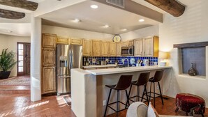 A modern kitchen with a central island, wooden cabinets, stainless steel appliances, and a bar area with stools. - Casa Feliz I Elegant 2-Bedroom Santa Fe Retreat (Santa Fe)