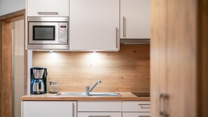 Eine Küche mit integriertem Mikrowellenherd, einer Kaffeemaschine und einem Spülbecken.