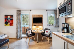 Una cocina moderna con microondas, cafetera y comedor con mesa y sillas.