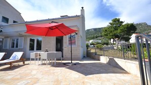 A stone patio with a red umbrella, a table, and lounge chairs. - Marvelous Escape Bol Island Villa With Pool (Bol)