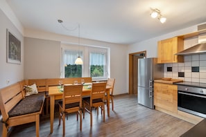 A modern kitchen with wooden cabinetry, a built-in oven, and a dining area with a bench and table.