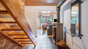 Un escalier en bois mène à un espace de vie doté d’une cheminée, offrant une vue sur l’extérieur et doté d’un sol carrelé.
