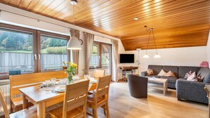 Un coin repas avec une table et des chaises en bois, un canapé et un téléviseur fixé au mur.