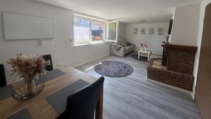 A modern living room with a dining area, a fireplace, and a large window.