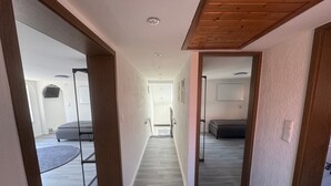 A hallway with wooden beams, a bed, a desk, and a chair.