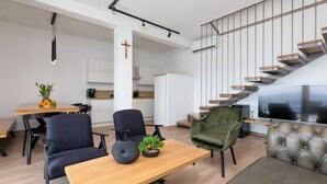 Uma sala de estar moderna com uma mesa de jantar de madeira, duas cadeiras, um sofá e uma televisão.