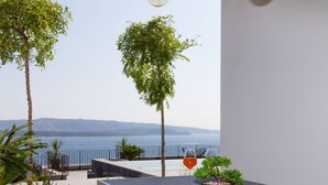 Uma varanda com vista para o mar, uma mesa com uma planta em vaso e uma cadeira.