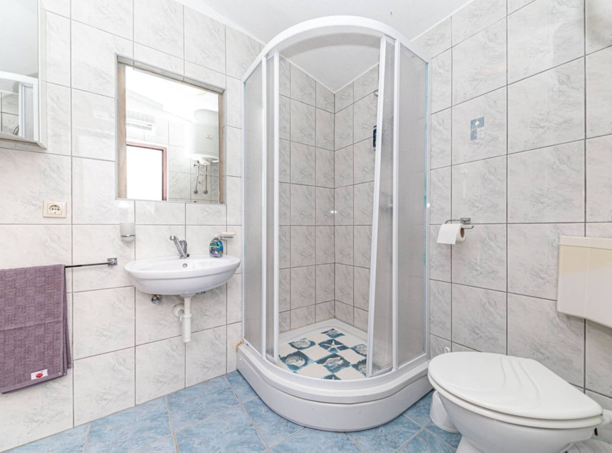 Een badkamer met douche, wastafel en toilet.