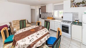 A compact kitchen with white cabinets, a gas stove, and a small refrigerator.