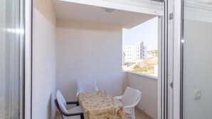A balcony with a table and two chairs, a view of buildings in the background, and a door to the right. - Charming and Cozy Okrug Gornji Apartment With Balcony (Okrug)