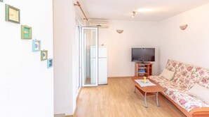 A living room with a sofa, a television, and a coffee table. There are framed pictures on the wall and a sliding door leading to another room. - Charming and Cozy Okrug Gornji Apartment With Balcony (Okrug)