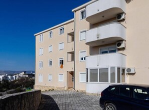Un edificio residencial de varios pisos con fachada color crema, ventanas blancas y balcones.
