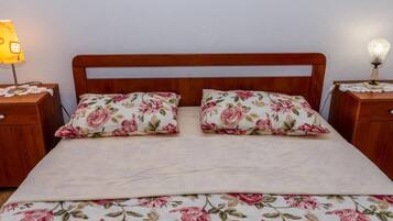 A bed with a floral bedspread and two matching pillows, flanked by wooden nightstands with lamps.