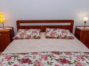 Una cama con cubrecama floral y dos almohadas a juego, flanqueada por mesitas de noche de madera con lámparas.