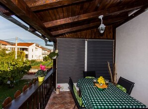 Una veranda riparata con tovaglia a scacchi, posti a sedere all'aperto e una lanterna appesa.