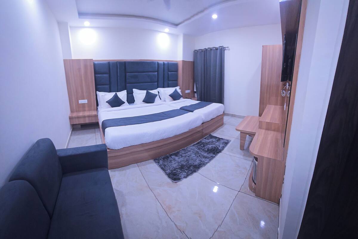 Un dormitorio moderno con una cama grande, cabecera de madera, televisor y una mesita.