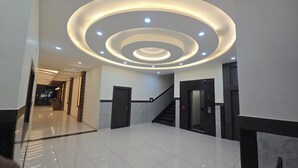 Um lobby moderno com um luminária circular, escada e elevador.