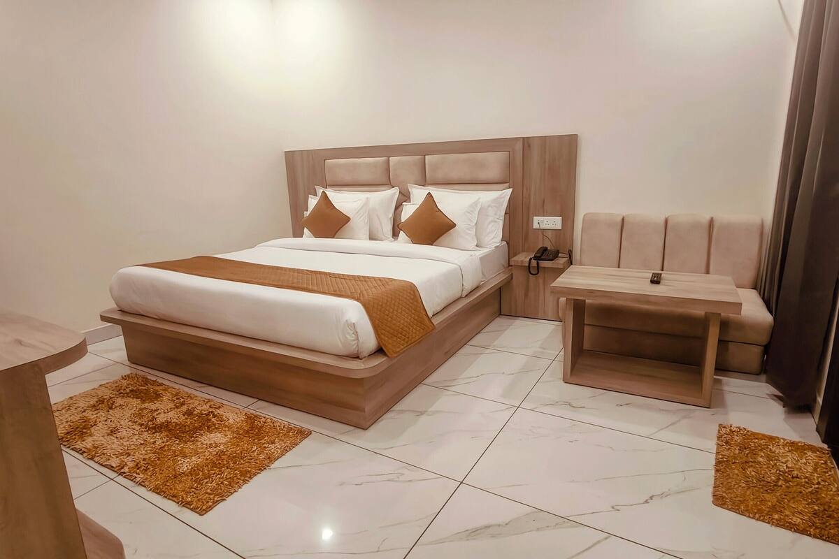 Una habitación de hotel moderna con una cama grande, una mesita de noche, un escritorio pequeño y un sofá.