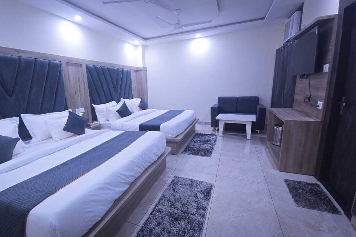 Una habitación de hotel con dos camas, un sofá, un televisor y un escritorio.