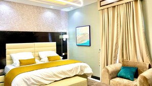 Una habitación de hotel moderna con una cama grande, una mesita de noche, una silla y un cuadro en la pared.