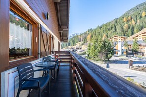 A balcony with wooden railings, a table, and chairs. - Duplex apartment in the village of Fontanazzo (Mazzin)