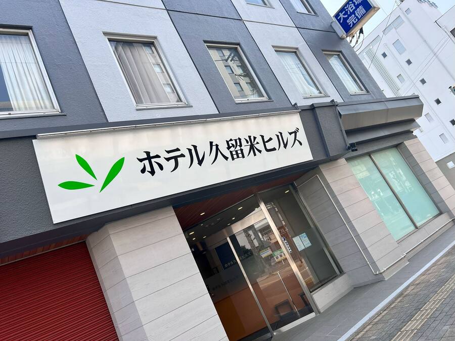 A hotel with a sign in Japanese, a modern facade, and a red awning.