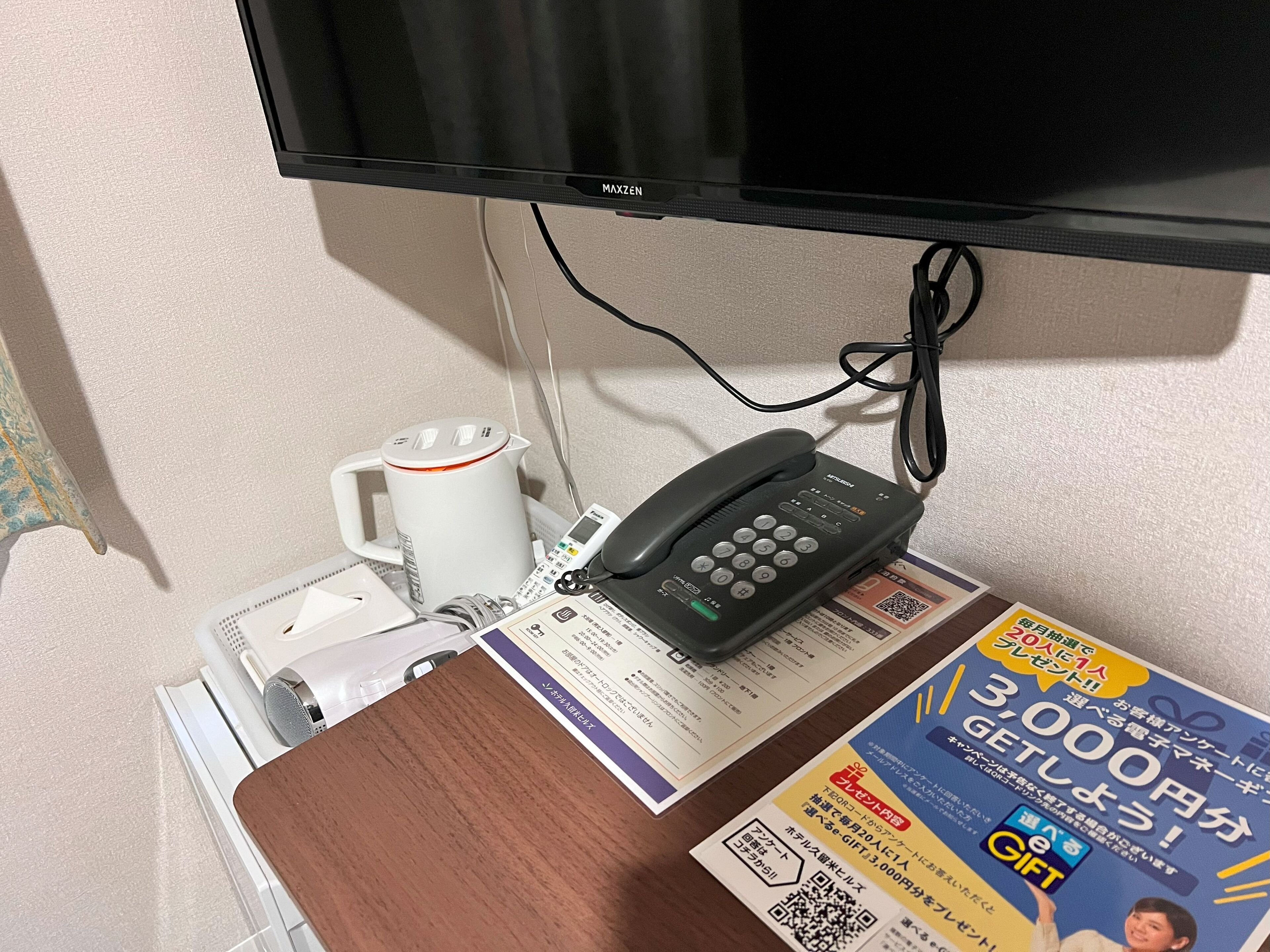 Ett skrivbord med en telefon, en mugg och en utskriven broschyr.