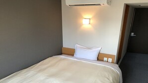 A hotel room with a bed, a wall-mounted light, and a door. - Hotel Kurume Hills (Kurume)