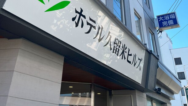 A hotel with a modern facade, featuring a prominent sign with a green leaf logo and Japanese text. - Hotel Kurume Hills (Kurume)